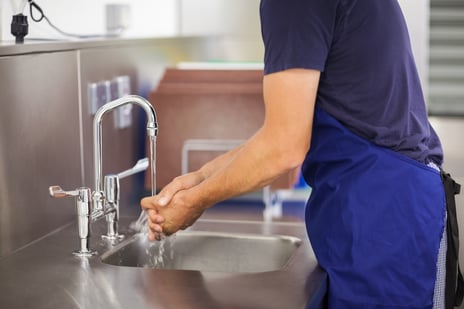 Kitchen porter washing his hands in professional kitchen