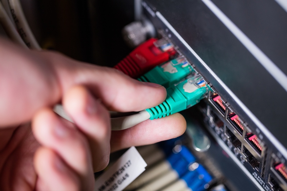 Close-Up of technician plugging ethernet in a rack mounted server in server room