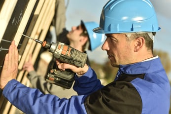 Construction worker using electric drill on building site-1