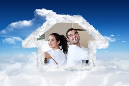 Radiant couple with unpacking boxes moving to a new house against bright blue sky with clouds