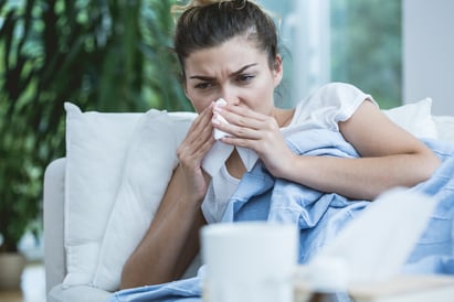 Sick woman with runny nose lying in bed