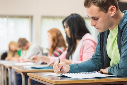 Side view of a group of young students writing notes in the classroom